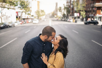 Romantic couple kissing while standing on road in city