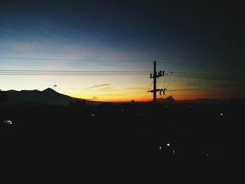Silhouette electricity pylon against sky during sunset