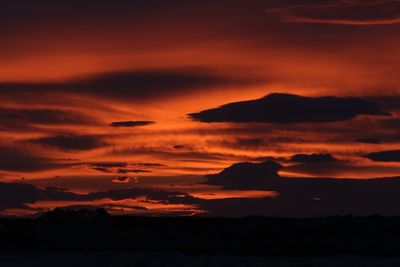 Scenic view of sea against dramatic sky during sunset