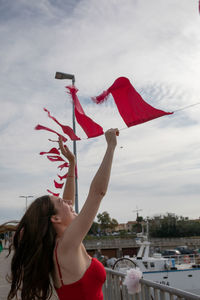 Cheerful woman holding flag in mid-air on pier