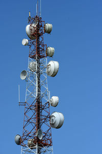 Low angle view of communications tower against blue sky