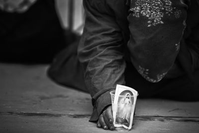 Low section of person holding photograph in disposable glass begging at night