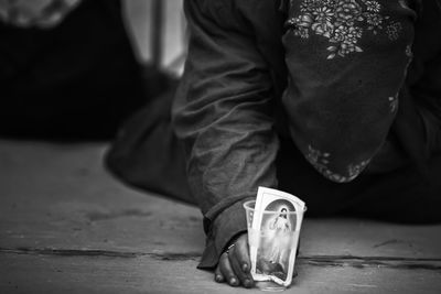 Low section of person holding photograph in disposable glass begging at night