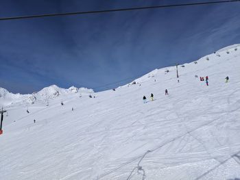 People skiing on snowcapped mountain against sky