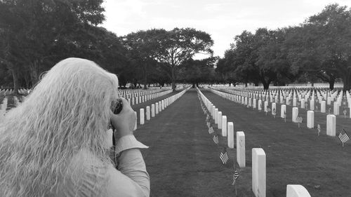 Rear view of woman photographing at cemetery