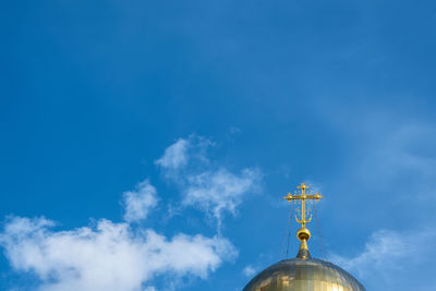 Low angle view of weather vane against blue sky