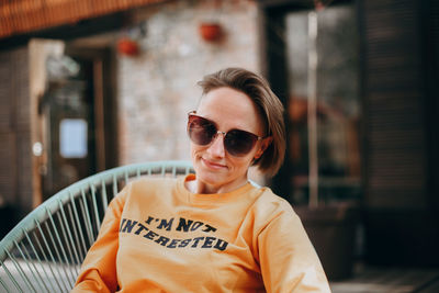 Beautiful young woman with short blond hair in casual clothing sitting and smiling.