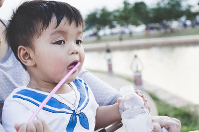 Cropped image of mother with cute son holding water bottle