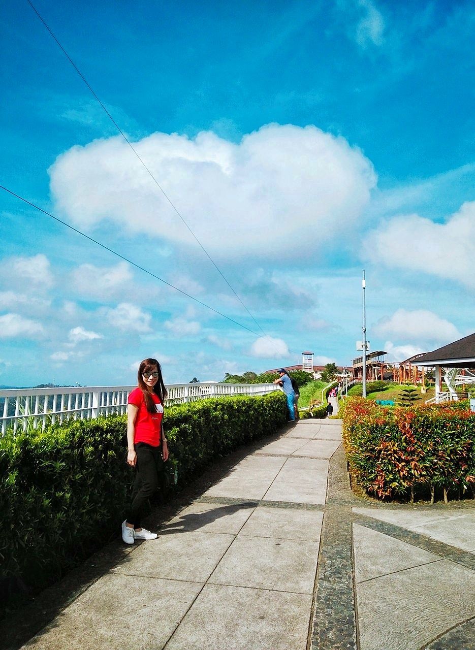 cloud - sky, sky, full length, one person, real people, nature, day, lifestyles, plant, footpath, women, females, sunlight, architecture, leisure activity, casual clothing, transportation, adult, young adult, outdoors