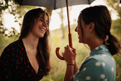 Portrait of smiling young women holding umbrella