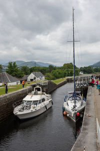 Boats moored in river against sky