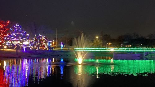 Illuminated fountain in city against sky at night