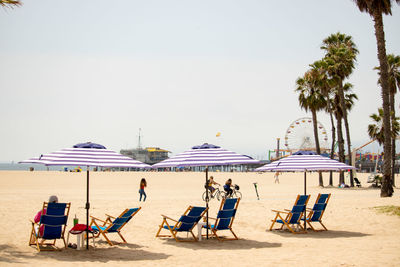 People relaxing on beach against clear sky