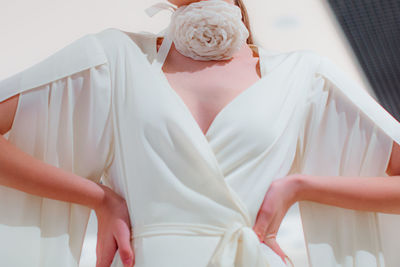 Elegant fashion details of white satin bridal dress and with a rose accessory around the neck.