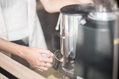 Midsection of woman holding mug on coffee grinder