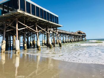 Pier on shore at beach against clear sky