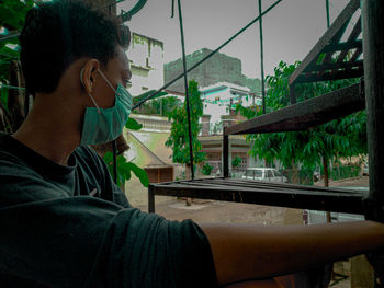 Side view of man looking through window