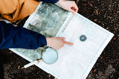 Unrecognizable hiker navigating with map and compass in countryside