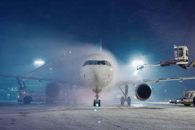 Deicing of airplane before flight. winter frosty night and ground service at airport.