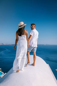 Rear view of friends on sea against clear sky