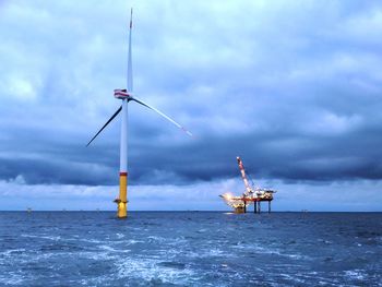 Windmill in sea against sky