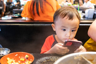 Portrait of boy holding food while sitting on table