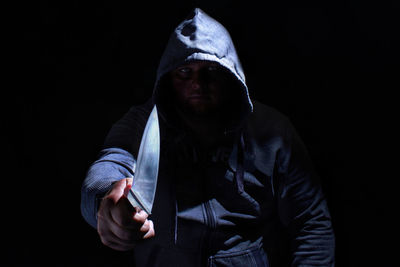 Portrait of man wearing mask against black background