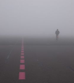 Person riding bicycle on road during foggy weather