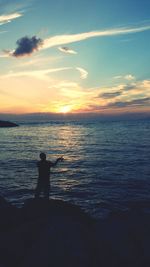 Silhouette of people in sea at sunset