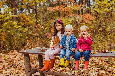 Full length of happy girl sitting on autumn leaves