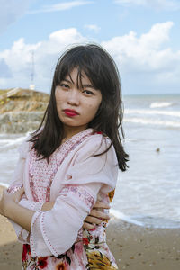 Portrait of young woman standing at beach