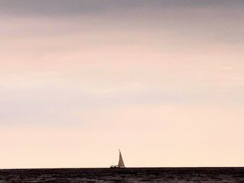 Distant view of sailboat in sea against sky