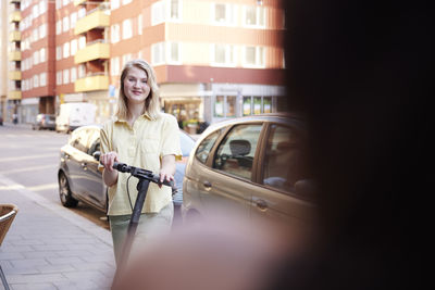 Smiling young woman riding electric scooter