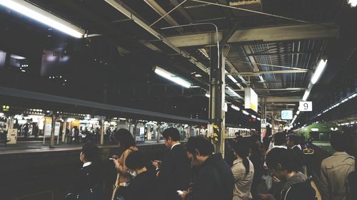 Group of people waiting on railway station platform at night