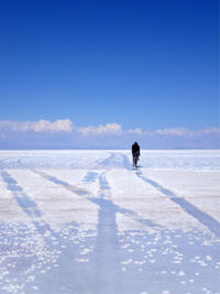 Man on riding bicycle on salt flat at salar de uyuni