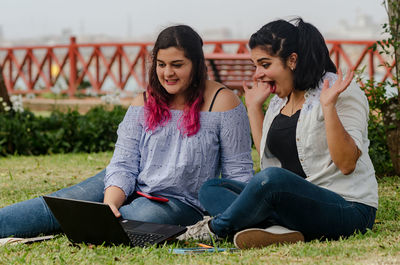 Cheerful friends using technology at park