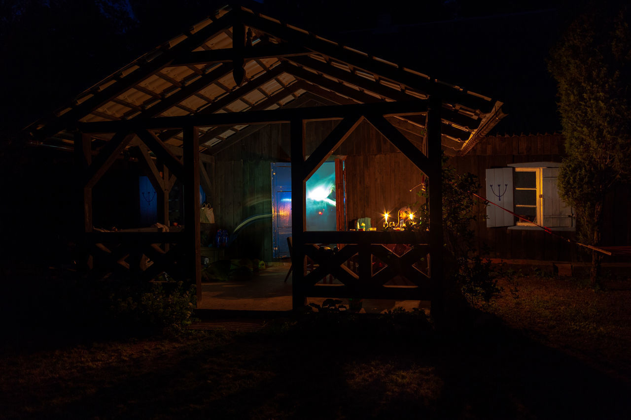 ILLUMINATED BUILDING BY HOUSE AT NIGHT