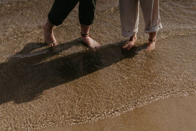 Low section of people walking on sand at beach