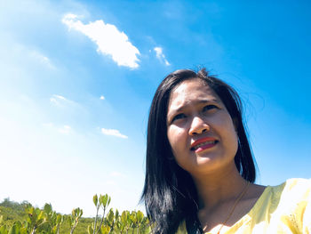 Portrait of smiling young woman against sky