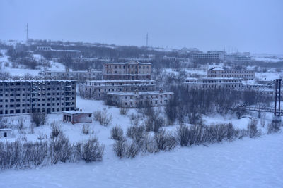 Snow covered trees and buildings against sky