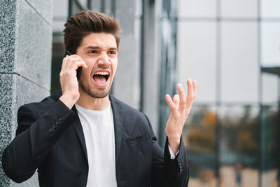 Frustrated businessman talking on phone outside office building
