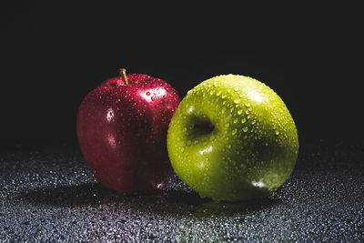 Close-up of wet apple on table against black background
