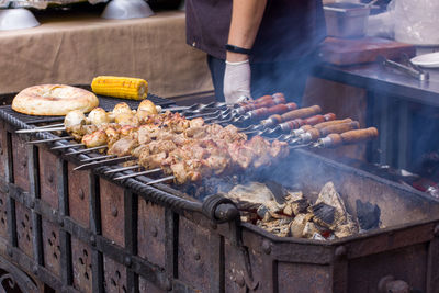 Midsection of man standing by barbecue grill at market stall