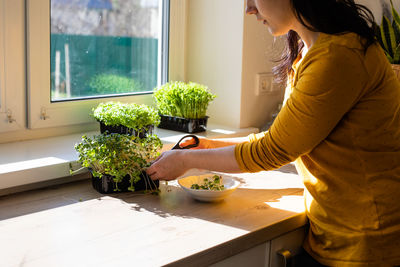 Midsection of woman standing by table at home