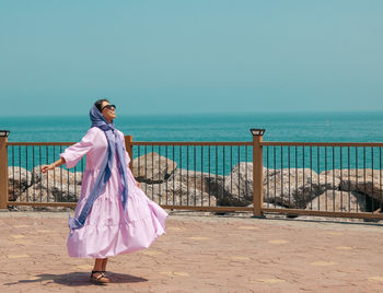 Woman standing on railing against sea