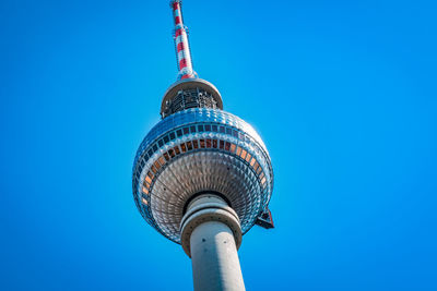 Low angle view of communications tower against blue sky