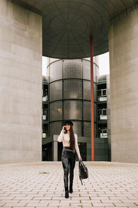 Full length of woman standing against building in city