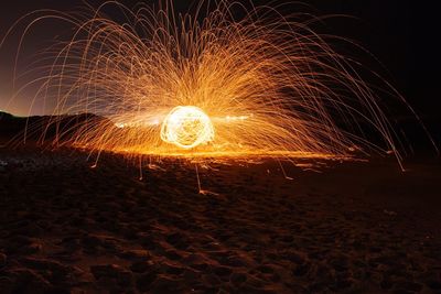 Illuminated wire wool at beach during night