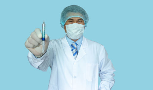 Portrait of man wearing mask against blue background