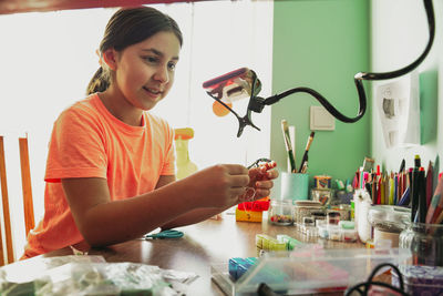 Girl recording jewelry making vlog through smart phone at home